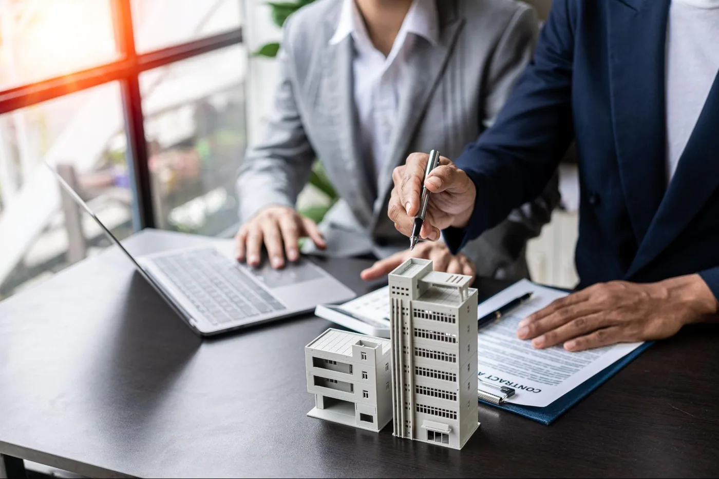 Property professionals reviewing plans beside an architectural model