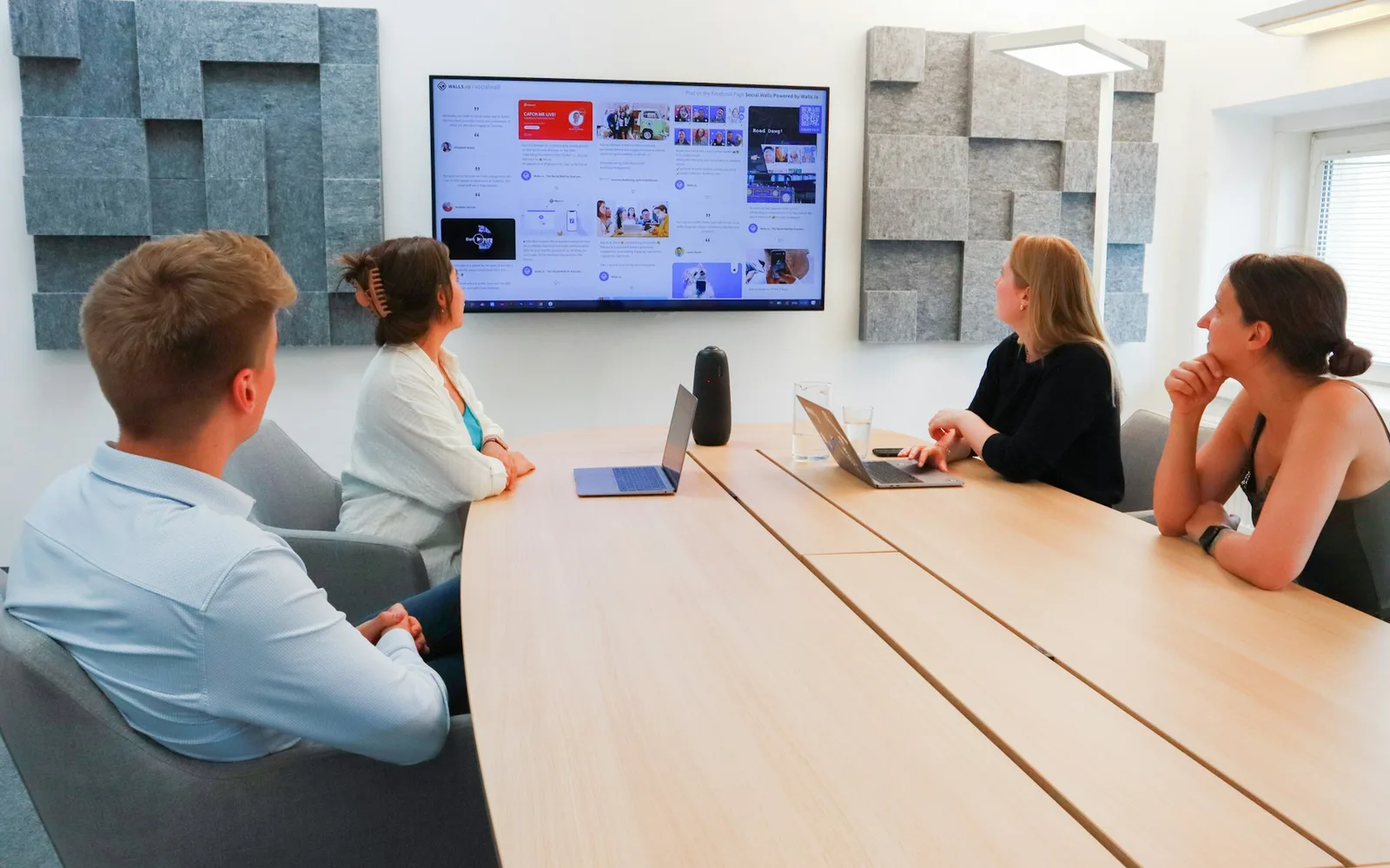 Hybrid meeting with a wall display, video bar and tabletop speaker